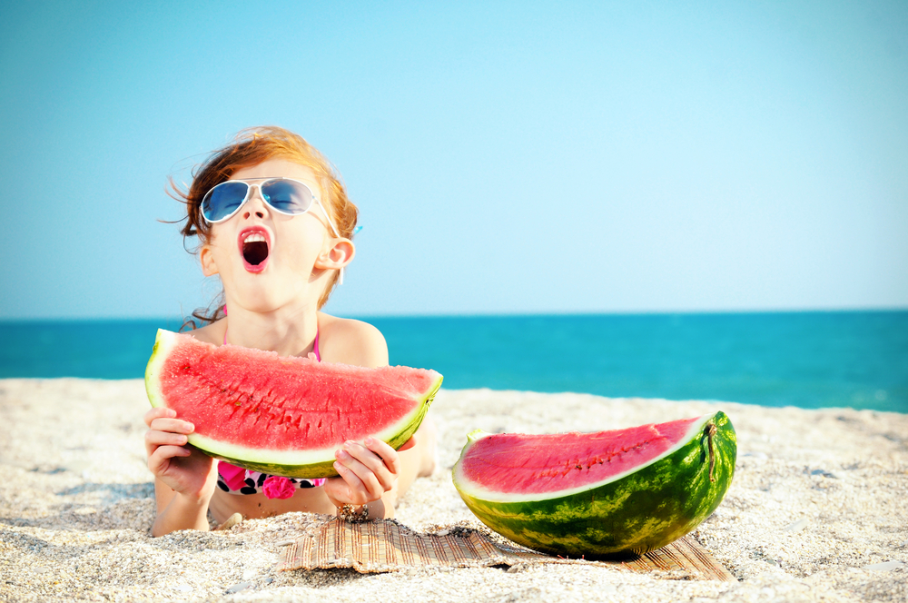 Child on the beach eating watermelon