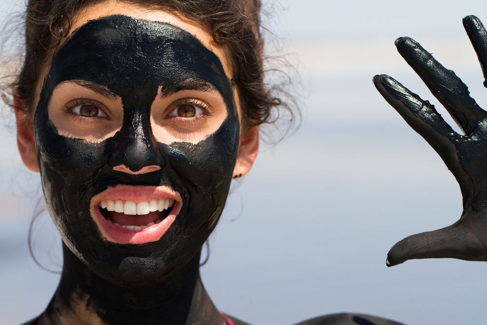 Beautiful young woman smiling with his mouth open in a mask out of clay