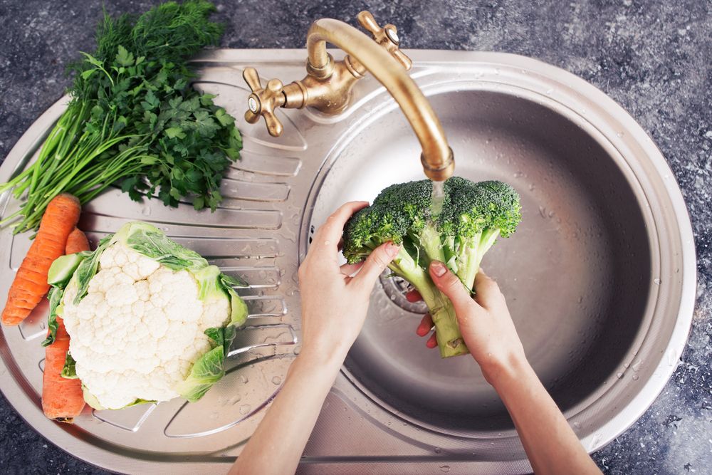washing vegetables in sink in kitchen