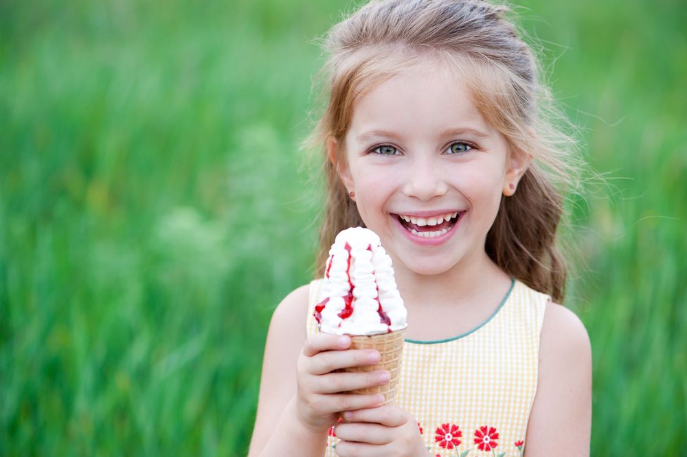 Beautiful little girl eats ice-cream in the summer