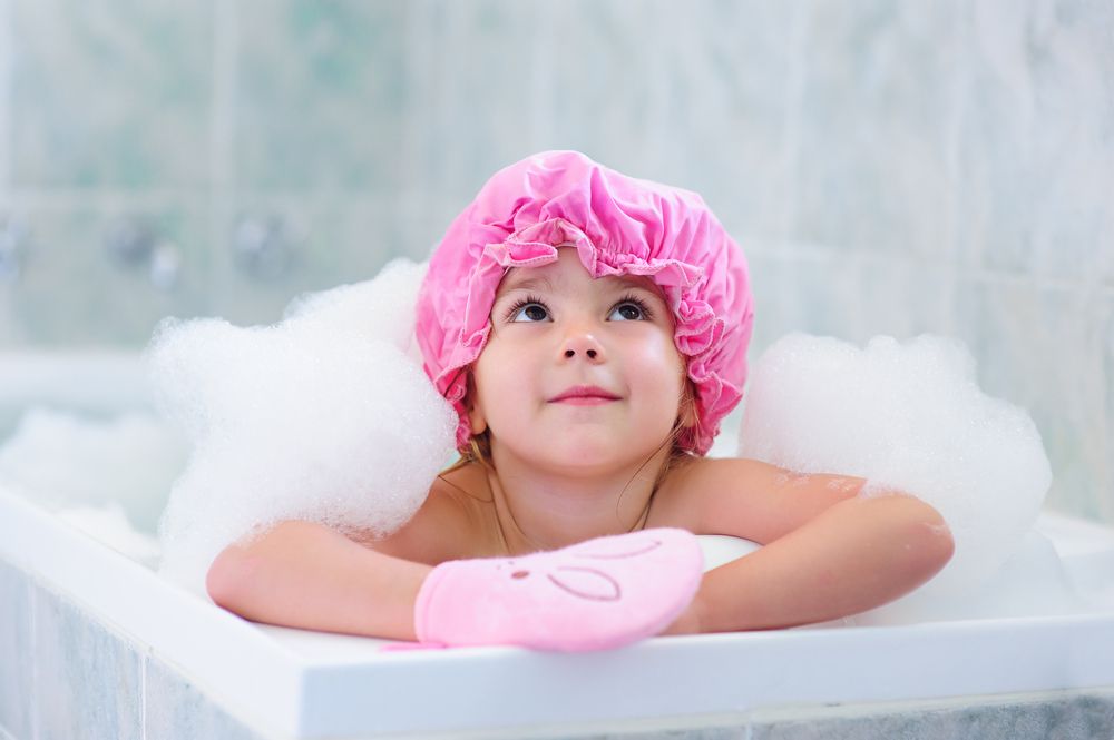 little-girl-washing-with-a-bubbles-in-bath-in-a-hat