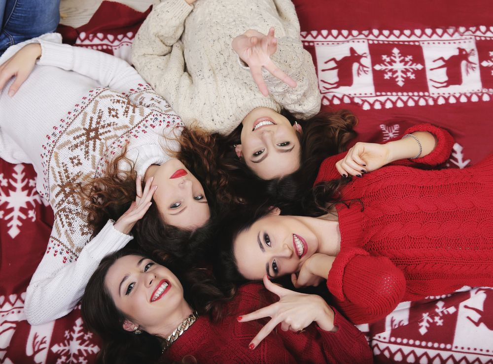 smiling-happy-girl-friends-group-in-new-years-sweater-lying-down