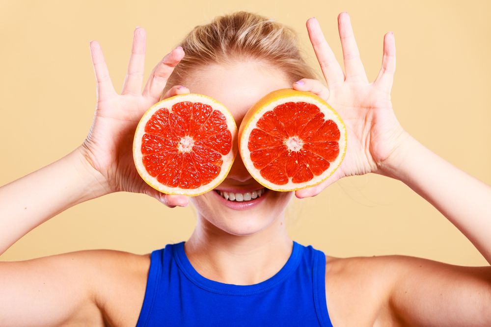 woman-girl-holding-two-halfs-of-grapefruit-citrus-fruit