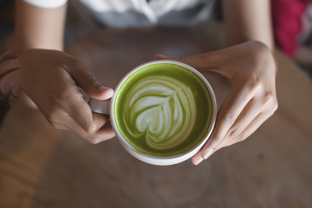 Woman holds green tea matcha latte