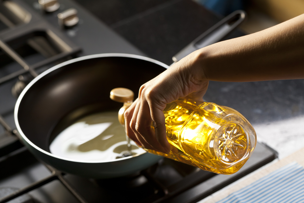 Pouring oil on frying pan maslo